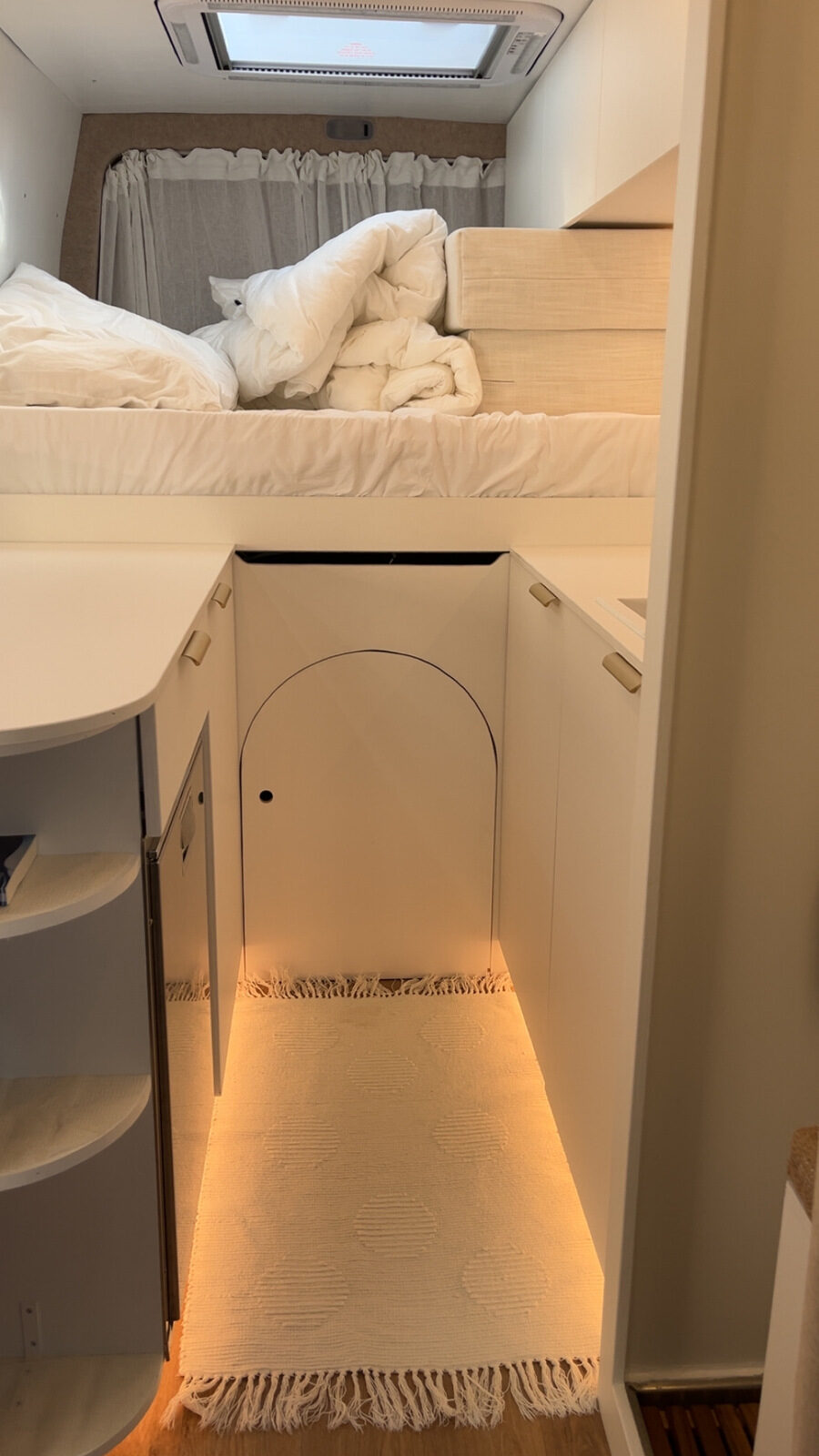 Großes Bett und beleuchtete Möbel im Camper